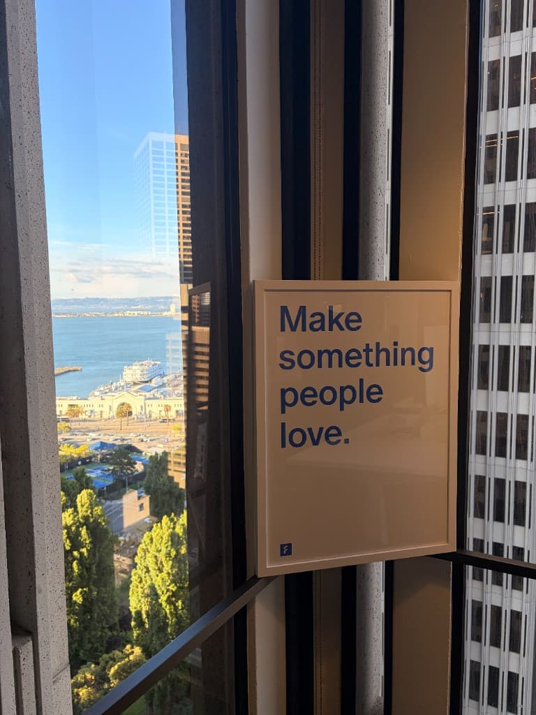 The 'Make something people love' poster in the Finta office, with the San Francisco bay through the window